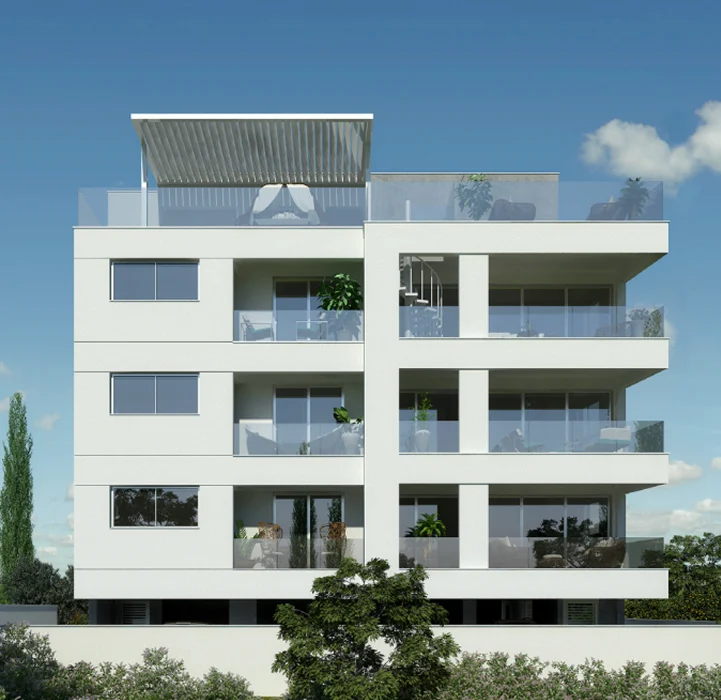 Modern white four-story apartment building with balconies, large windows, potted plants, and a rooftop terrace with a pergola, set against a blue sky with a few small clouds and greenery in the foreground.