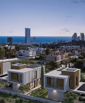 Modern white villas with flat roofs in a row, surrounded by greenery, overlooking a coastal cityscape with high-rise buildings and the sea at sunset with a partly cloudy sky.
