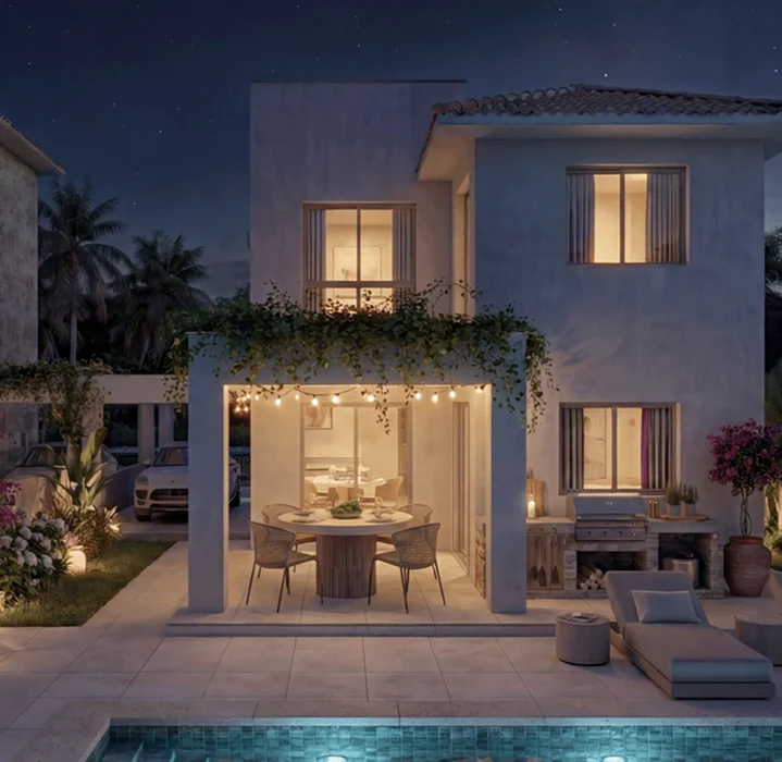 Modern white four-story apartment building with balconies, large windows, potted plants, and a rooftop terrace with a pergola, set against a blue sky with a few small clouds and greenery in the foreground.
